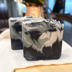 Black and white marbled soap bar on a white cloth with a blurred background